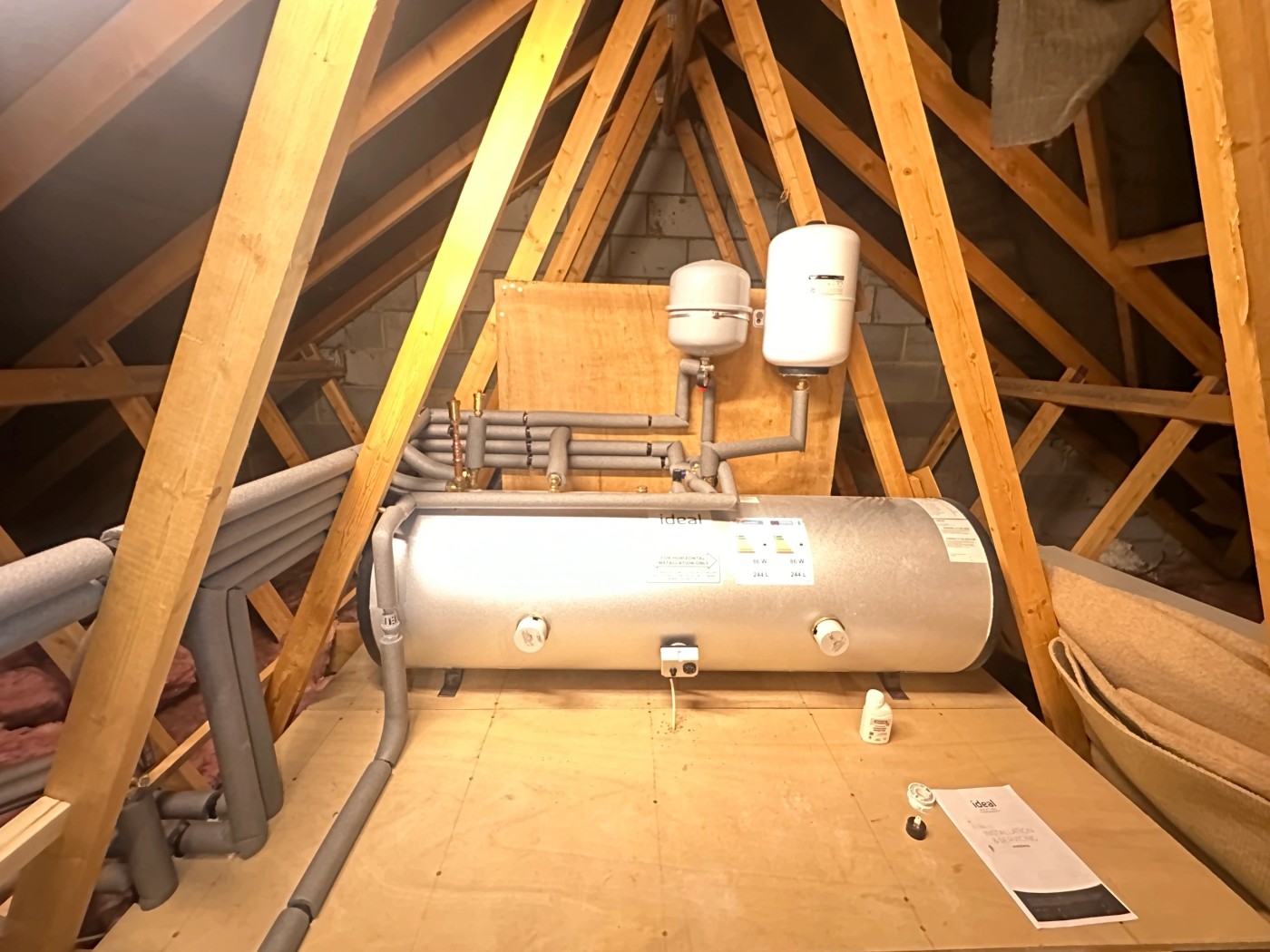 An Ideal unvented hot water cylinder with insulated pipework, professionally installed in a loft by AJGas Ltd